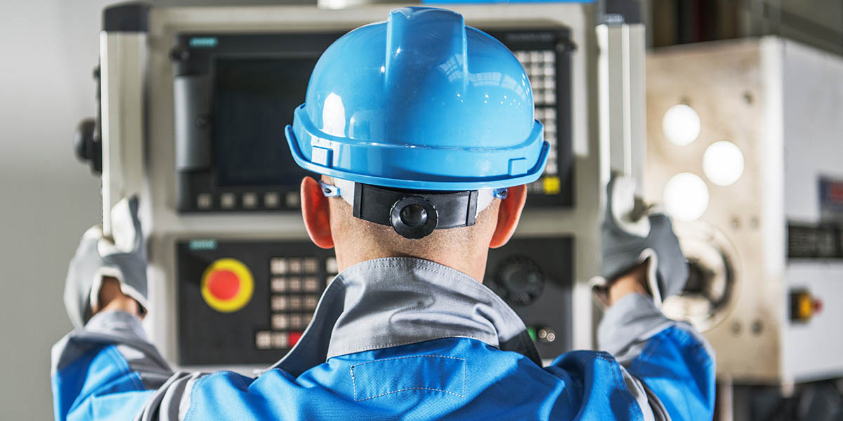 Caucasian CNC Operator in Front of Machine Operating Console. Metalworking Concept.